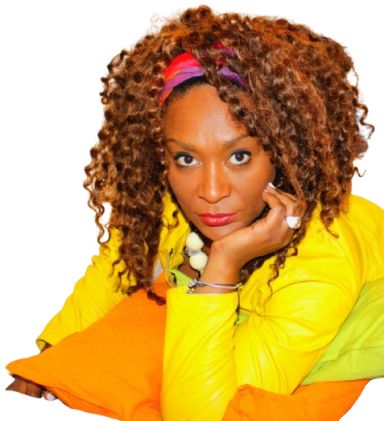 Woman with curly hair, wearing a yellow jacket and colorful pillows, looking directly at the viewer.